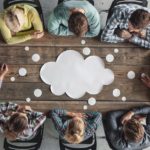 Hipster_business_teamwork_brainstorming_planning_meeting_concept,_people_sitting_around_the_table_with_white_paper_shaped_like_dialog_cloud