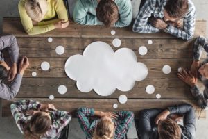 Hipster_business_teamwork_brainstorming_planning_meeting_concept,_people_sitting_around_the_table_with_white_paper_shaped_like_dialog_cloud