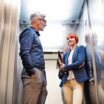 Two_business_people_in_the_elevator_in_modern_office_building.