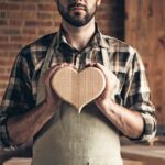 Free_time_lifestyle_people_happiness_happy_smile_person_dream_dreamy_concept._Closeup_photo_of_beautiful_small_little_wooden_ideal_cute_heart_hold_brutal_bearded_guy_in_casual_outfit