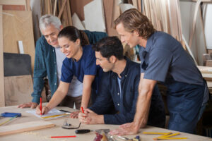 Team_of_carpenters_working_on_blueprint_at_table_in_workshop