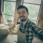 Close_up_photo_of_successful_professional_workman_feel_positive_make_selfie_hold_hand_show_his_renew_hardwood_wooden_shelf_production_in_home_house_garage