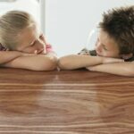 Happy_brother_and_sister_resting_on_dining_table