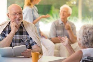 Smiling_man_in_glasses_holding_a_book_and_talking_to_woman_in_wheelchair