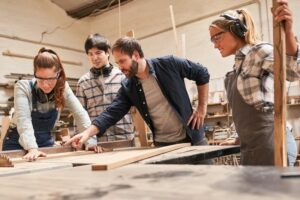 Carpenter_apprentices_with_trainers_at_the_circular_saw_in_the_carpentry_workshop