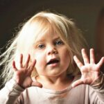 Caucasian_child_girl_looking_at_the_camera_indoors_showing_her_hands_palms